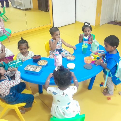 Feeding assistance session at Waddle Kids Daycare — caretaker helping children during lunch break